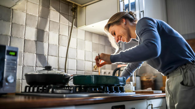 Mid adult woman with amputated arm cooking in kitchen at cozy home. Low angle view 