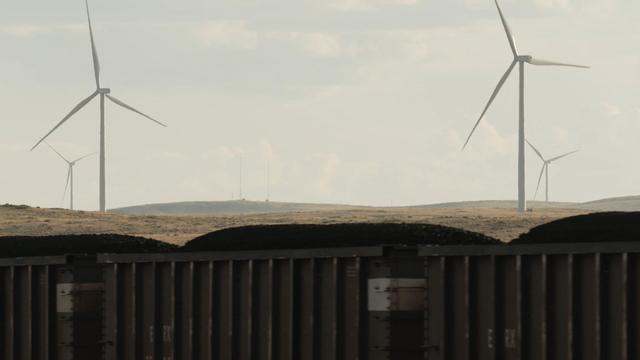 Coal train passes in front of Wyoming wind farm 
