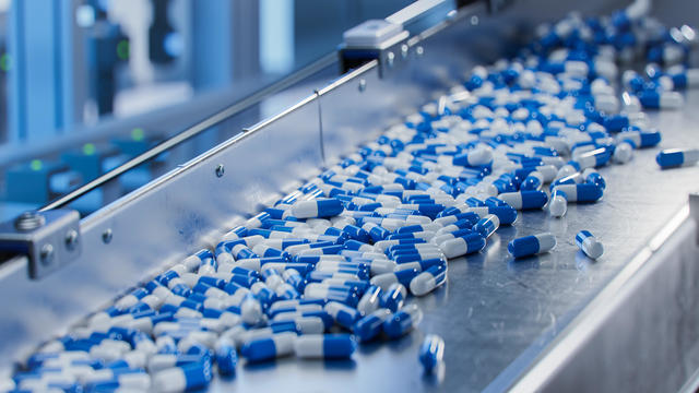 Blue Capsules on Conveyor at Modern Pharmaceutical Factory. Tablet and Capsule Manufacturing Process. Close-up Shot of Medical Drug Production Line. 