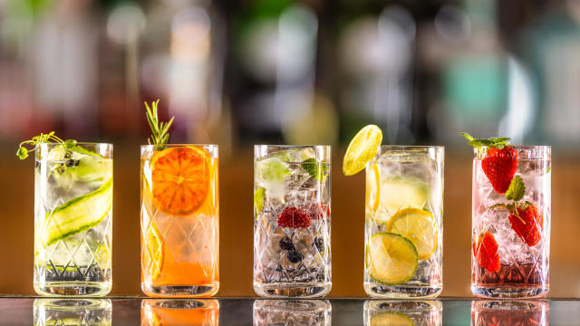 Five gin tonic cocktails in wine glasses on bar counter in pup or restaurant. 