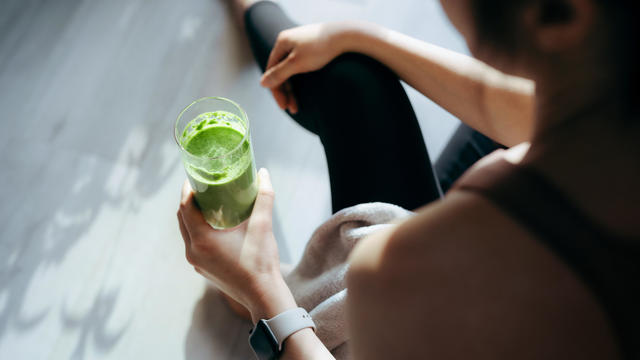 Over the shoulder view of woman taking a break, refreshing with green juice 