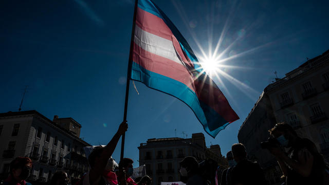 Demonstrator waving the Trans flag attends a protest where 